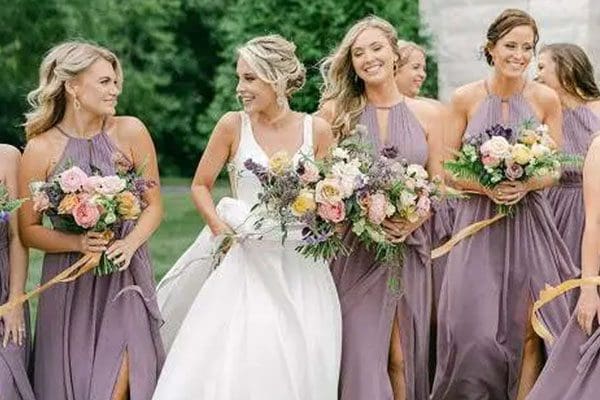 A group of women in purple dresses holding flowers.