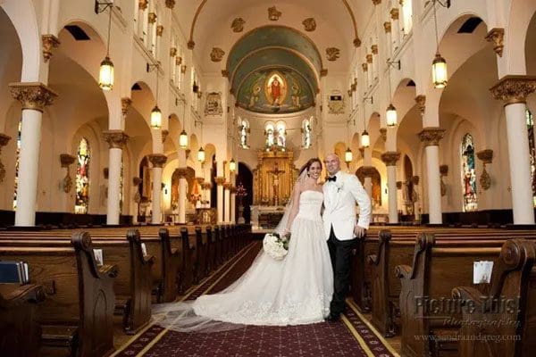 A bride and groom pose in the aisle of an old church.