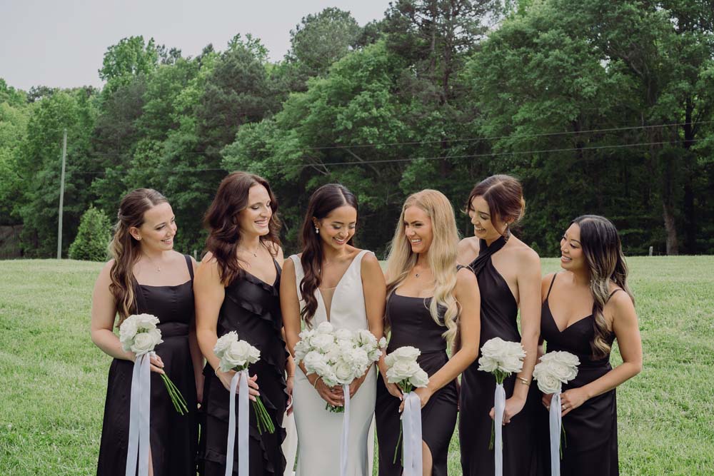 Bridesmaids in black dresses with white flowers.